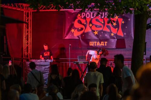 Večerni koncert, na odru DJ, pred njim občinstvo.