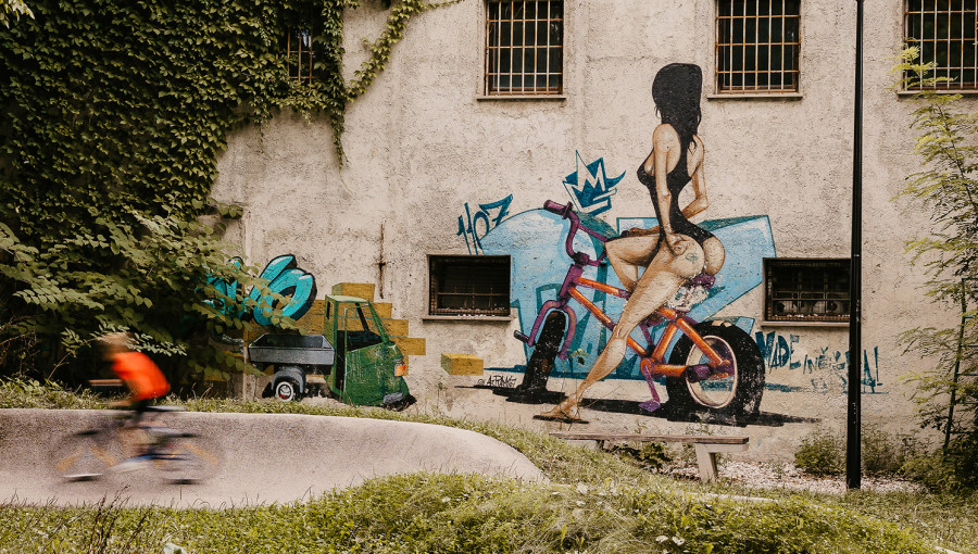 A graffiti of a woman in a swimsuit sitting on a bicycle is painted on the wall.