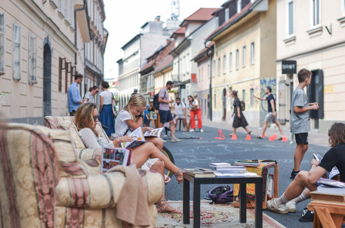 Ljudje berejo na kavcih na ulici.