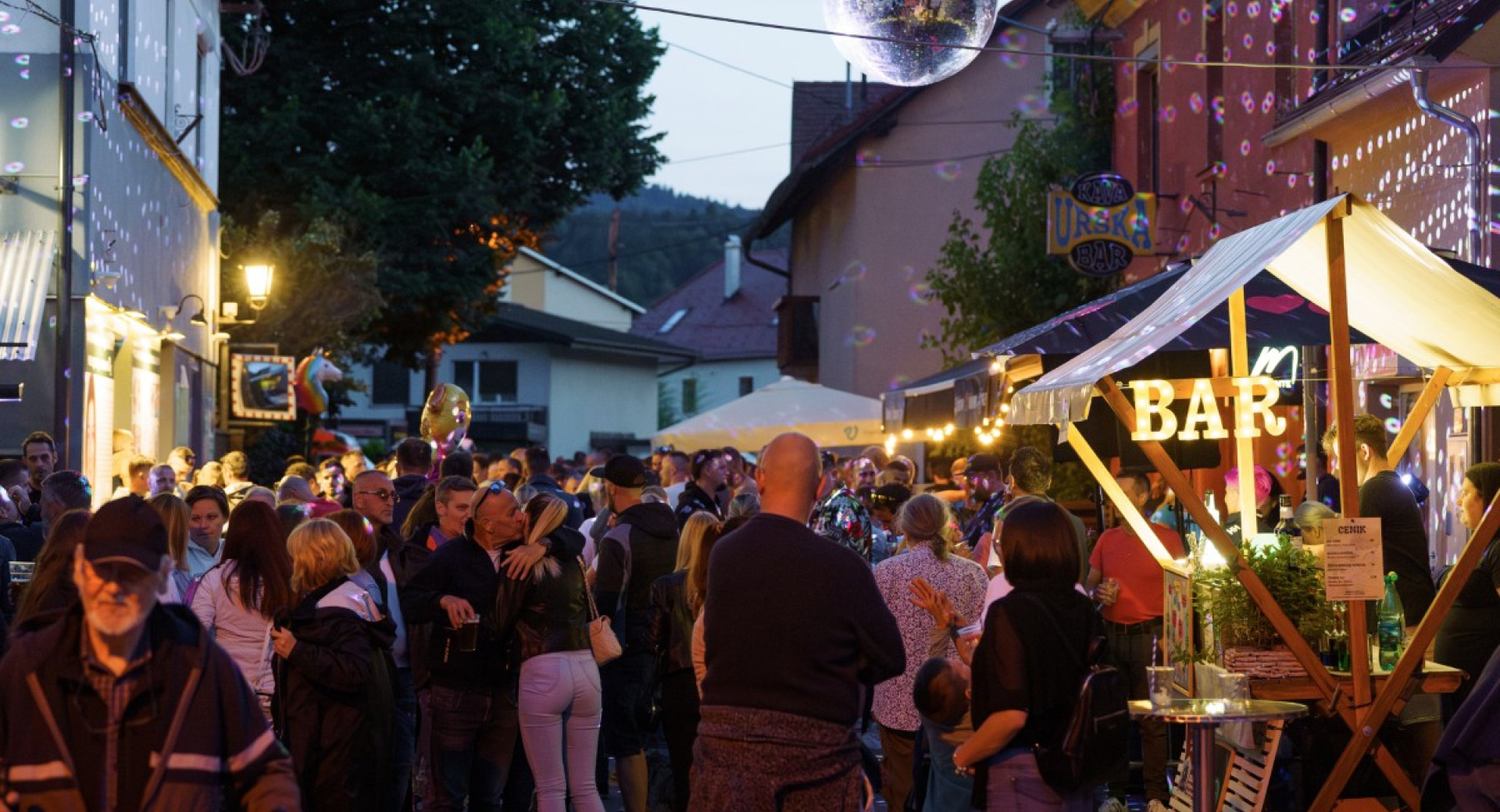 People are socialising on a decorated street with a disco ball.