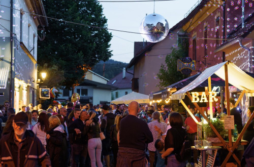 People are socialising on a decorated street with a disco ball.
