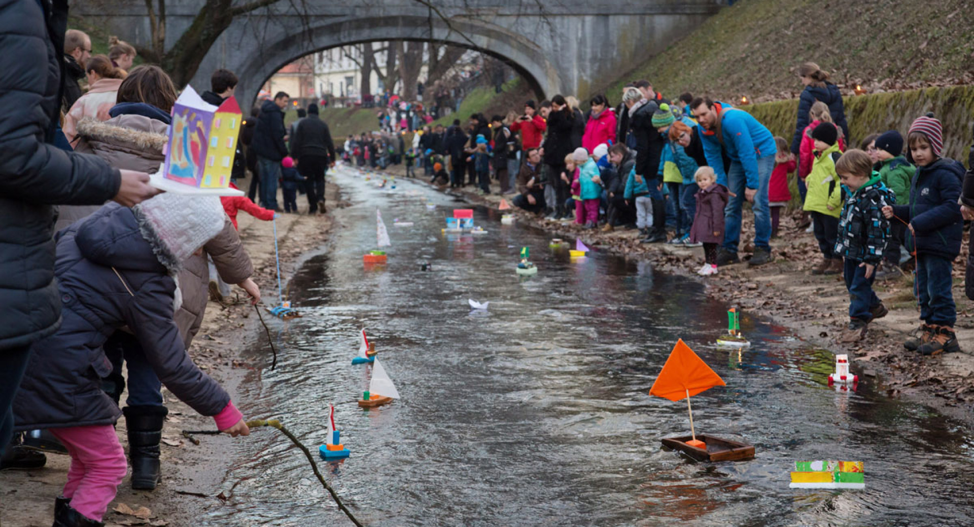 Ljudje ob reki spuščajo ladjice za Gregorjevo.