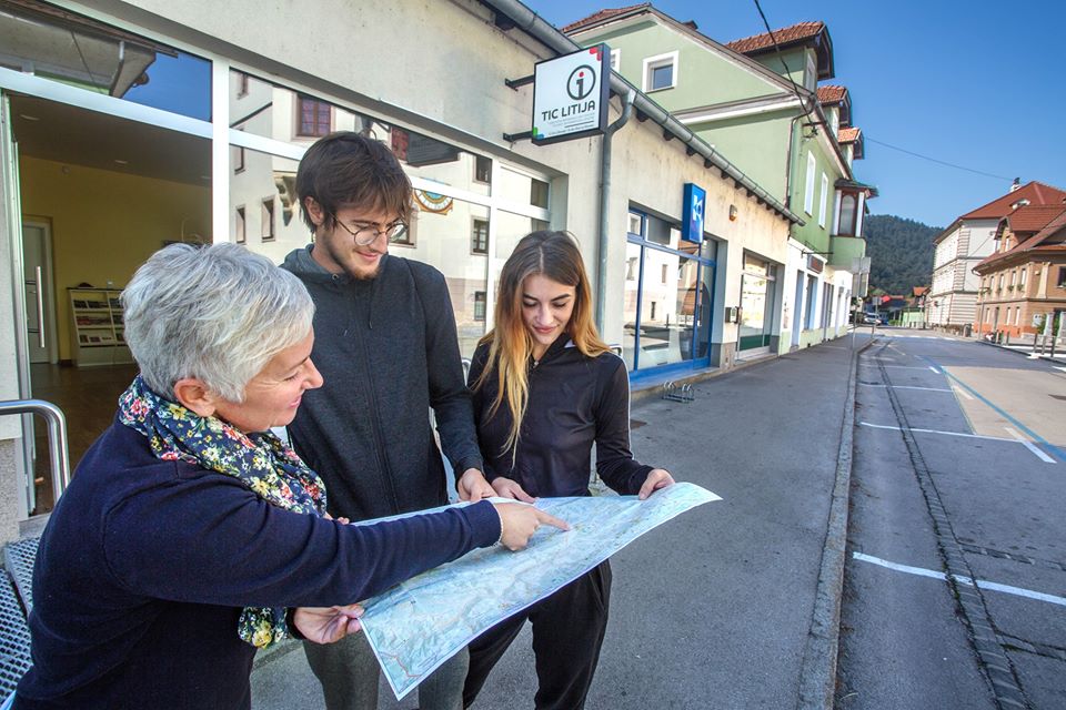 Drei Personen betrachten eine Karte vor dem Touristischen Informationszentrum Litija.