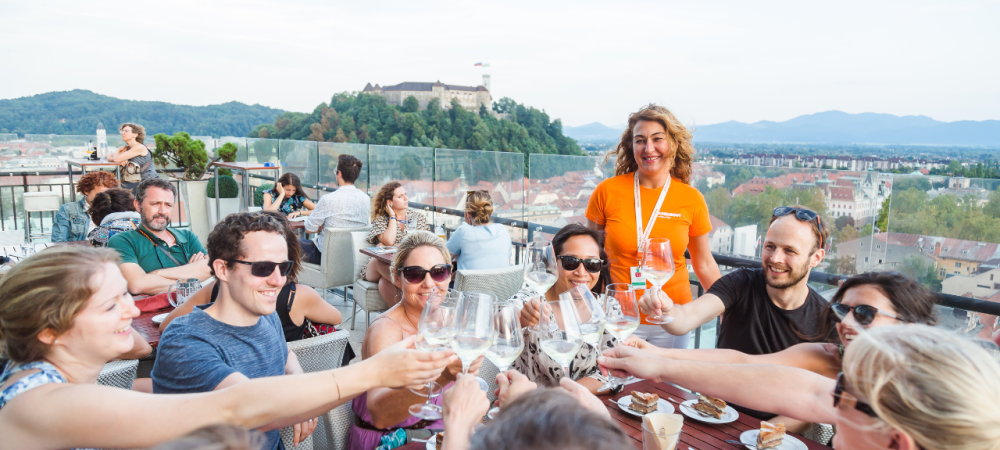 People toasting with wine, with a castle on a hill in the background.