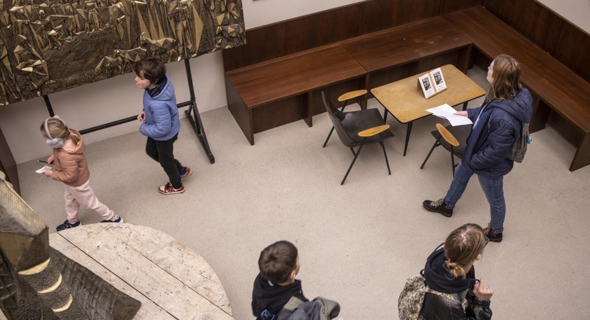 Overhead view of visitors of different ages viewing artworks on display in a gallery.