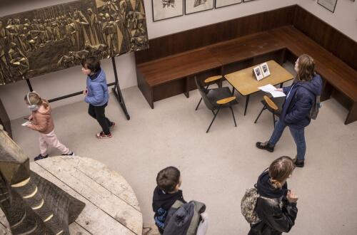 Overhead view of visitors of different ages viewing artworks on display in a gallery.