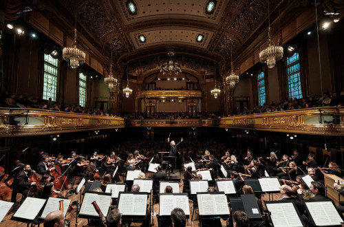 orkester na odru, v ozadju barocna dvorana s publiko
