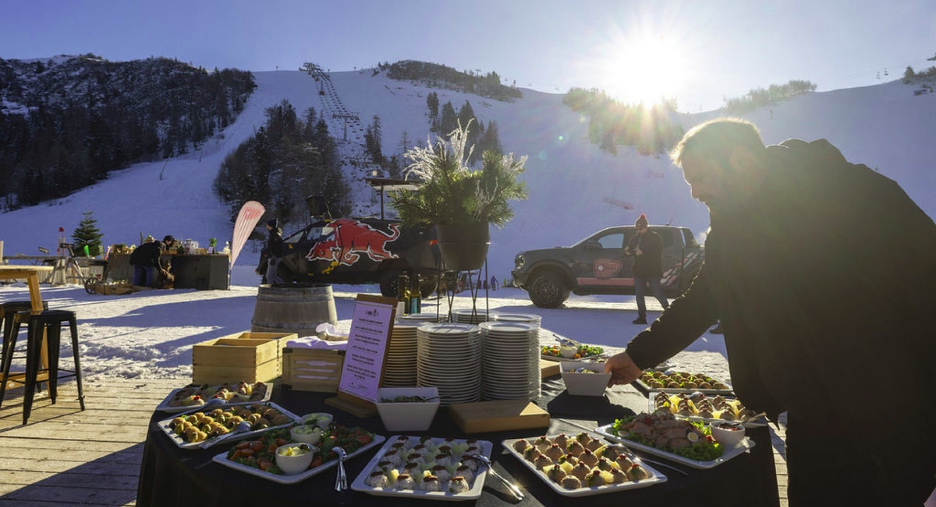 Obložena okrogla miza ob vznožju smučarskih prog, ob njej moški.
