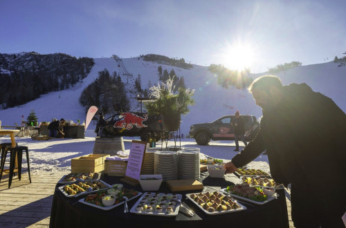 Obložena okrogla miza ob vznožju smučarskih prog, ob njej moški.