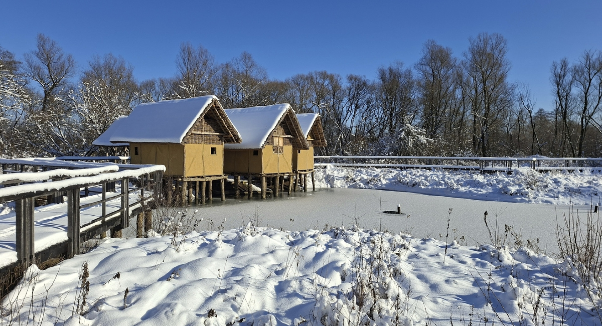 Lesene hiške v naravi sredi zasnežene pokrajine.