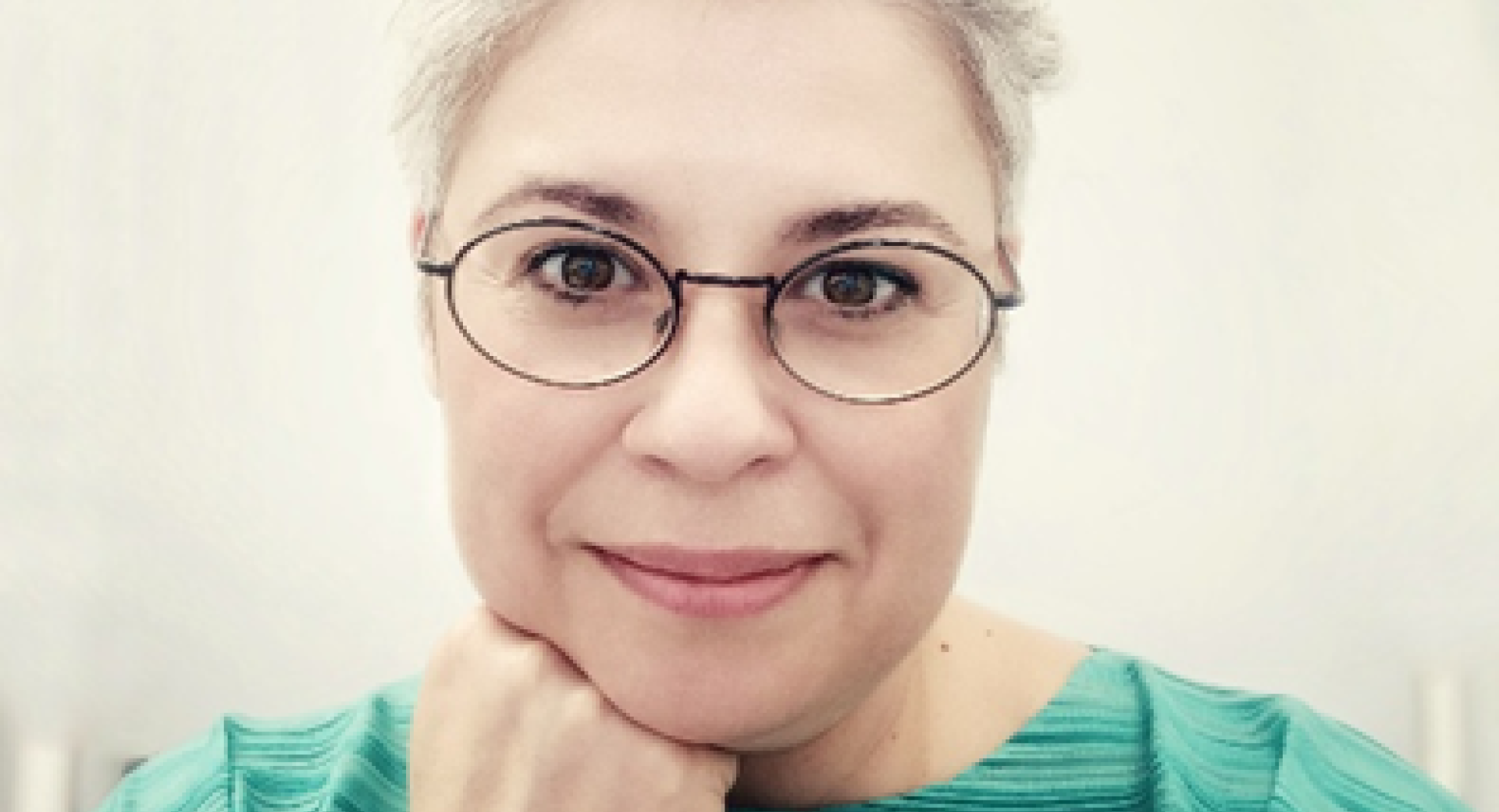 A blonde girl with glasses wearing a green T-shirt.