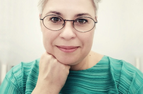 Svetlolaso dekle z očali v zeleni majici.