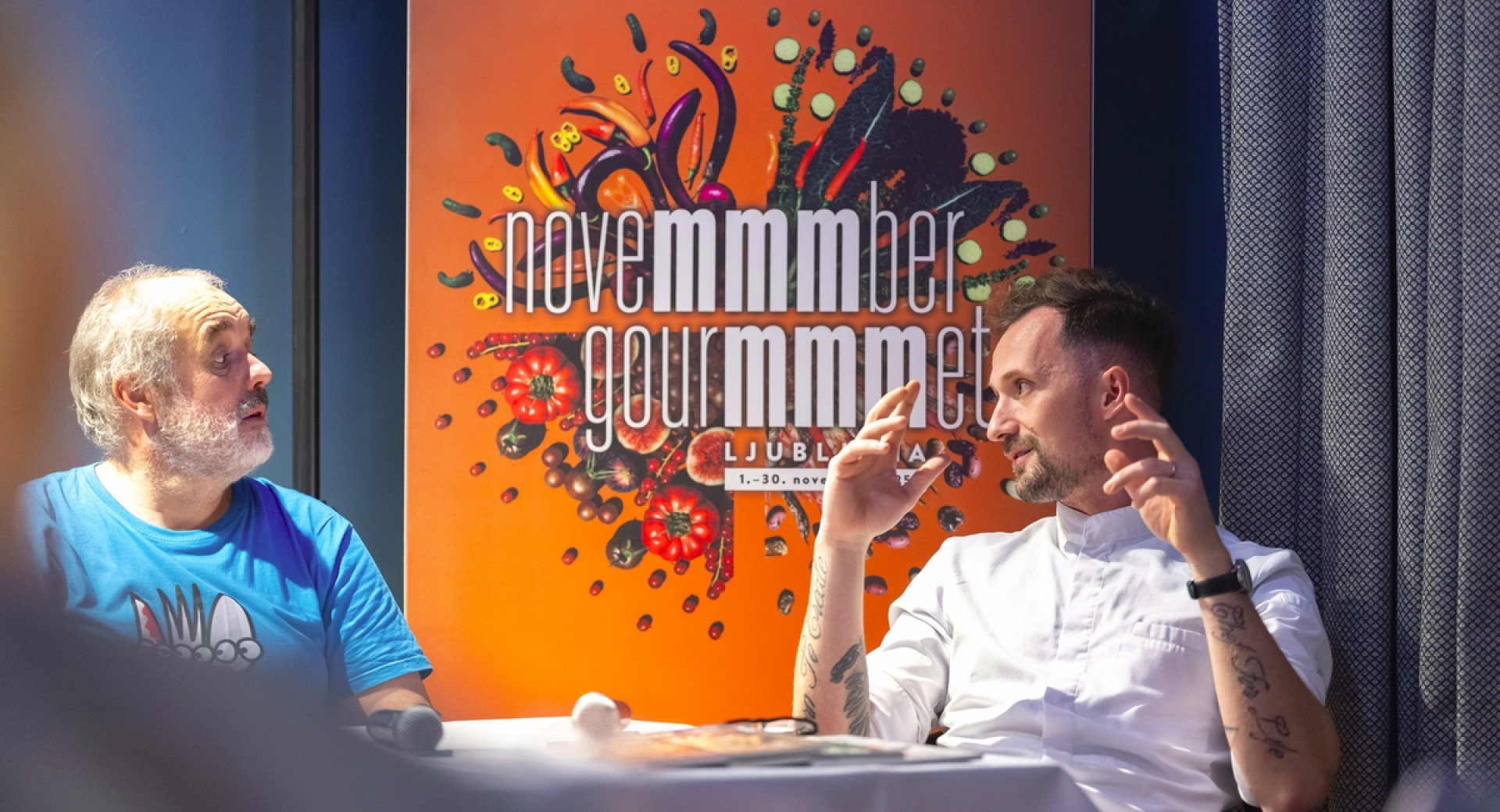 Dve osebi se pogovarjata ob mizi.