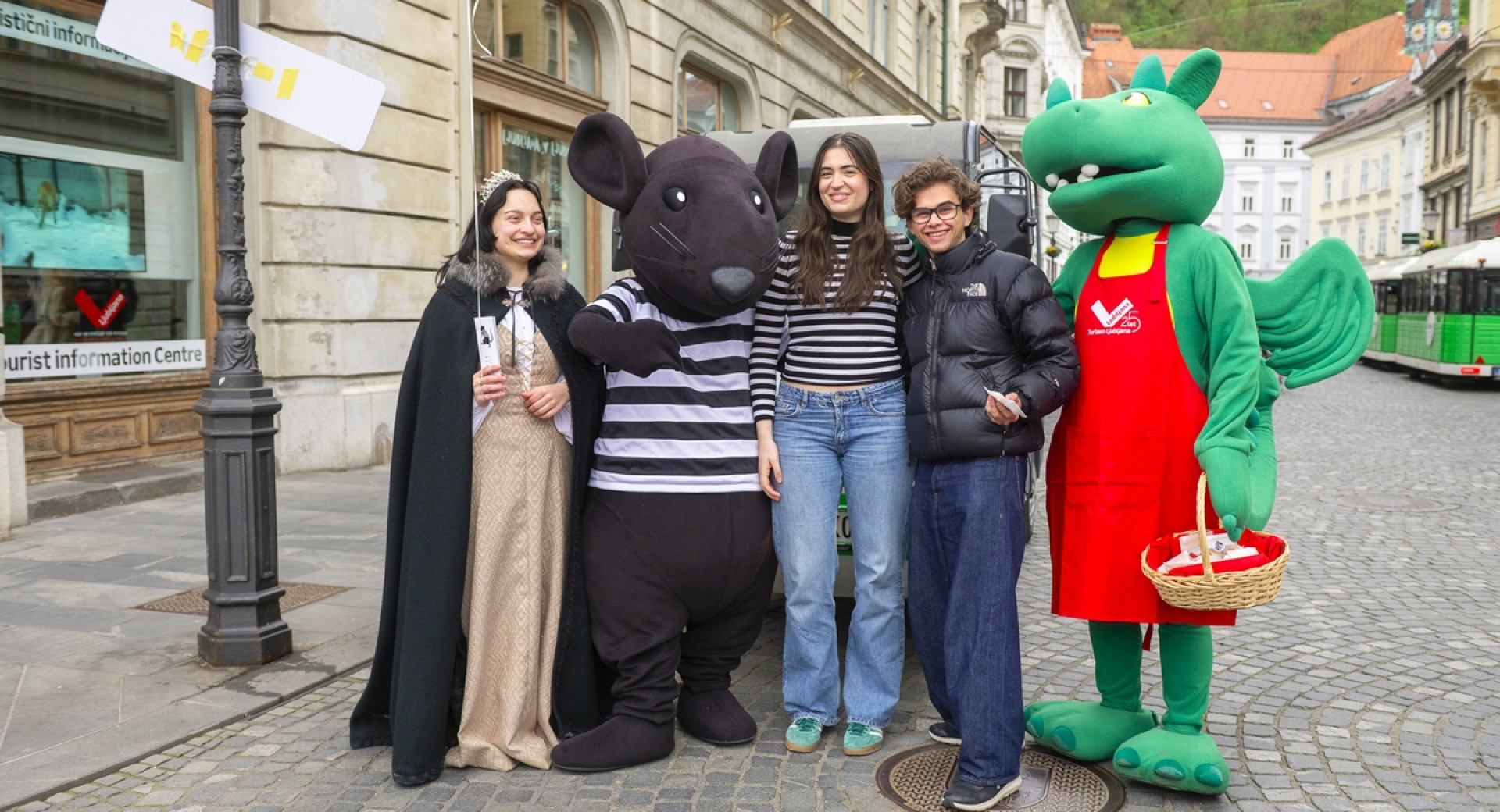 Pred objektivom je pet oseb, dve sta maskoti zmaja in podgane, ena je v kostumu grajske gospe.