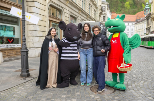 Pred objektivom je pet oseb, dve sta maskoti zmaja in podgane, ena je v kostumu grajske gospe.