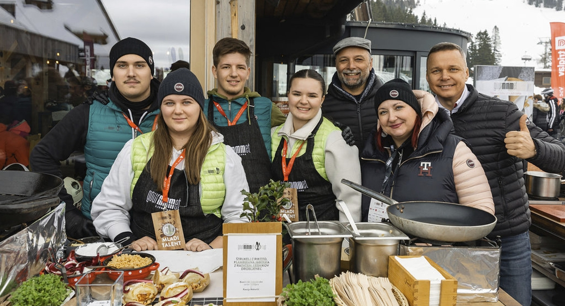 Skupina ljudi pred naborom pripravljenih jedi za postrežbo.