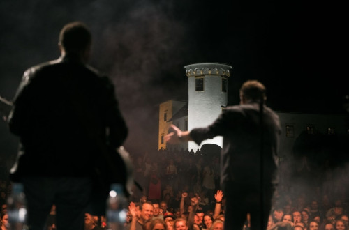 Koncert, na odru glasbenika, pred njima občinstvo.