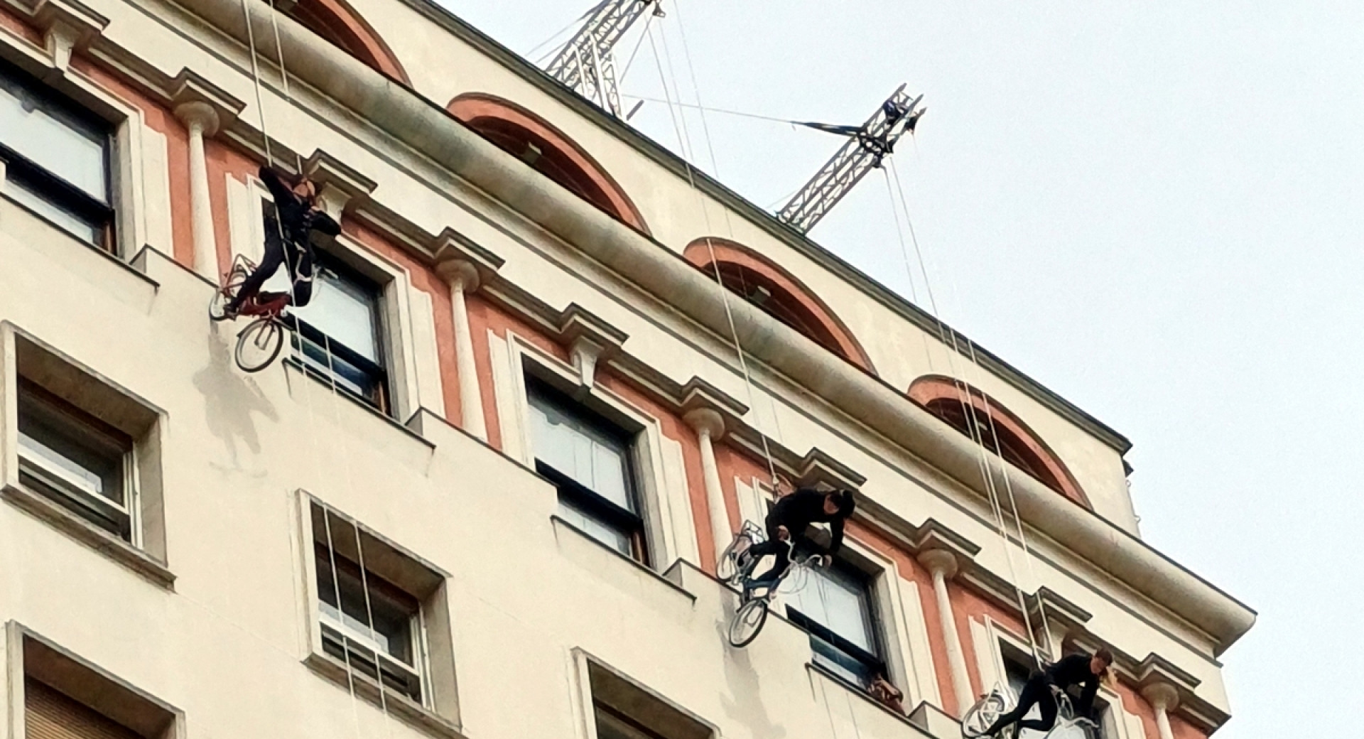 Kolesarji se spuščajo vertikalno po stavbi, zavarovani z vrvrmi.