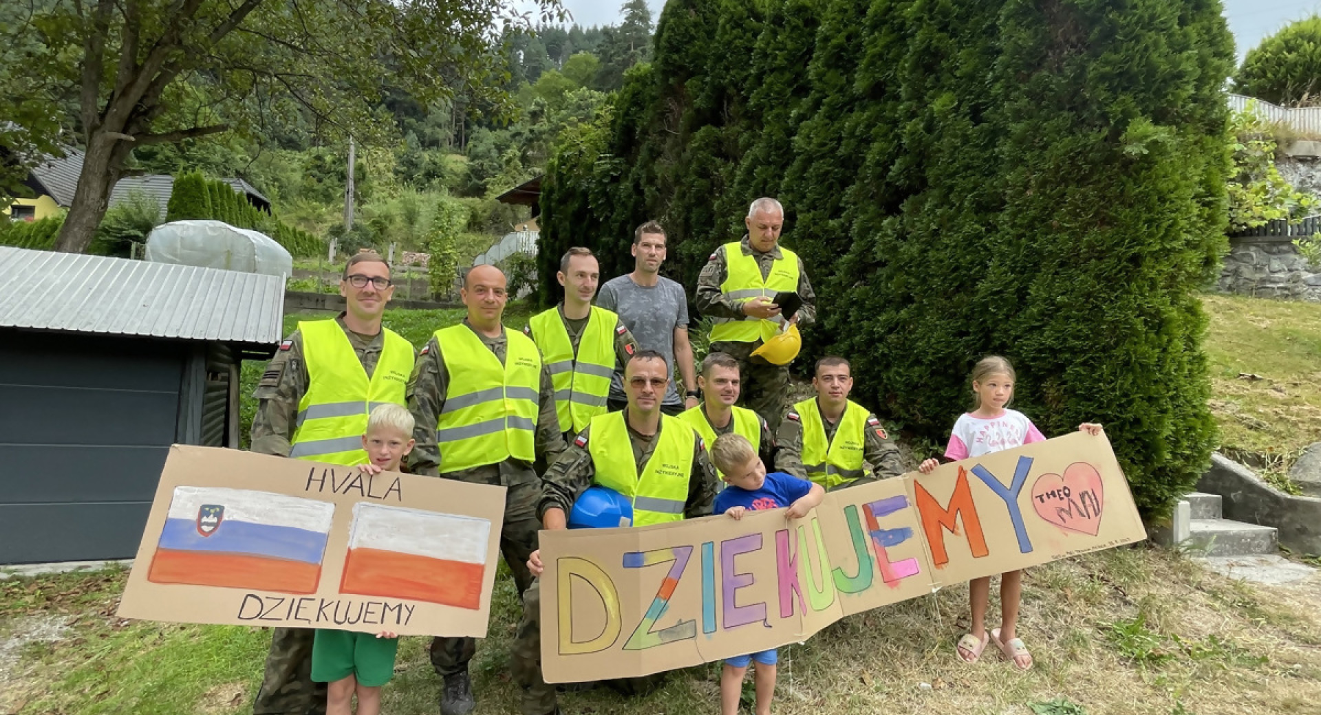 Skupina ljudi z rumenimi delovnimi brezrokavniki drzi transparent.