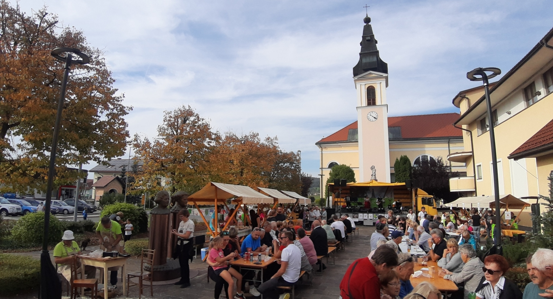 Ljudje sedijo ob mizah na prostem na prireditvi.