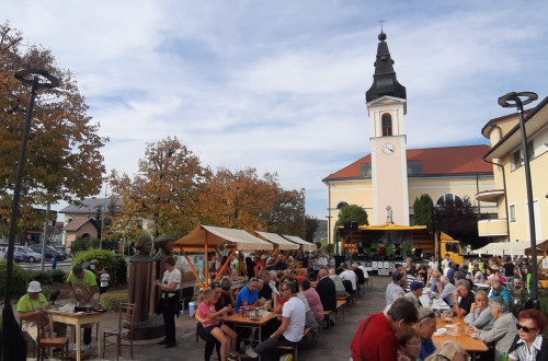 Ljudje sedijo ob mizah na prostem na prireditvi.