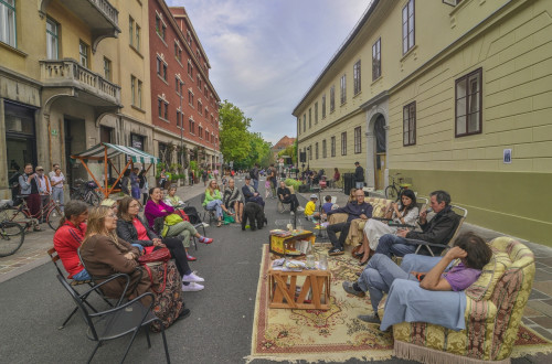 Ljudje sedijo v foteljih in na stolih sredi ulice.