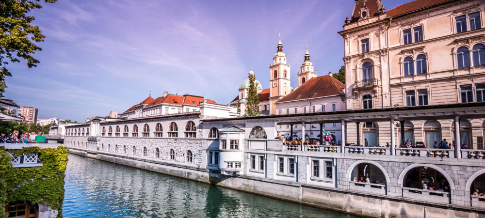 Plečnik's arcades by the river, with the cathedral in the background.