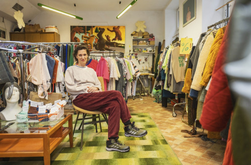 Oseba sedi sredi prostora, polnega oblačil.