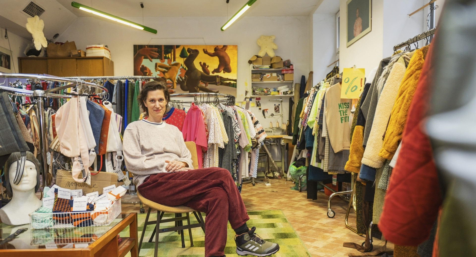 Oseba sedi sredi prostora, polnega oblačil.