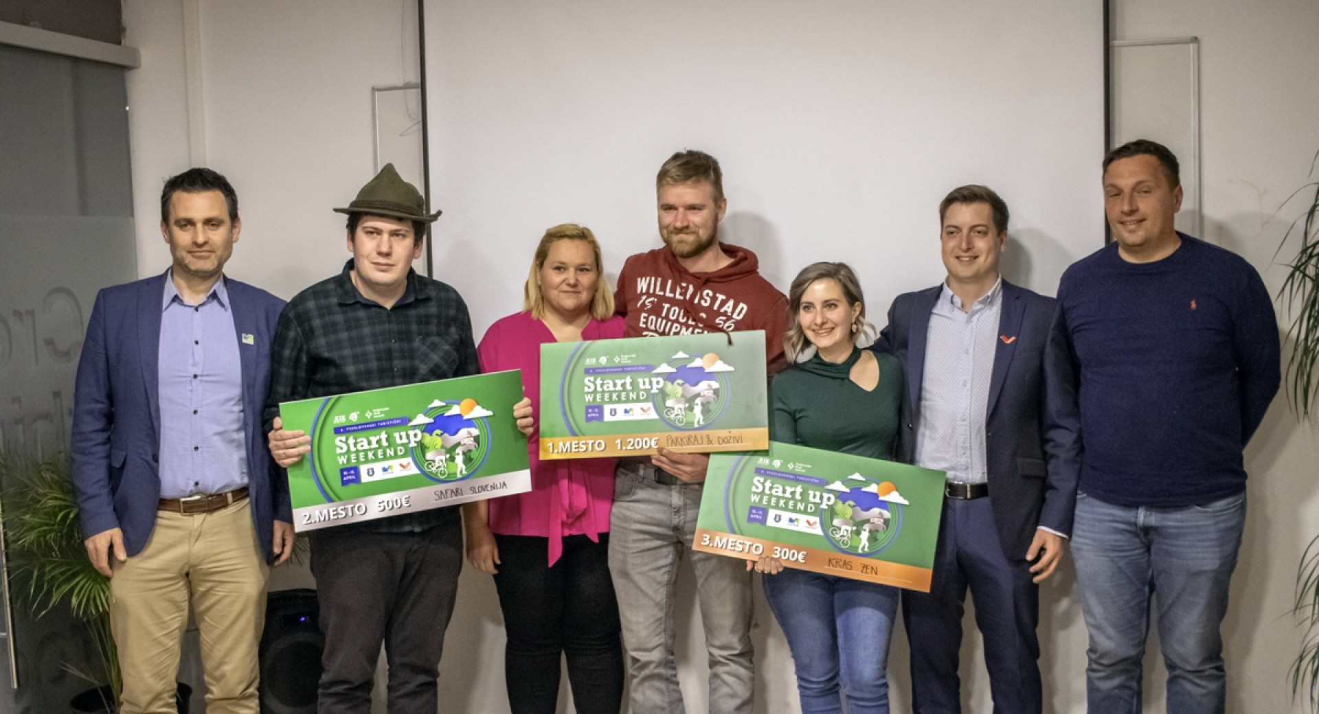 Skupina ljudi pred objektivom s tremi večjimi boni za nagrado.