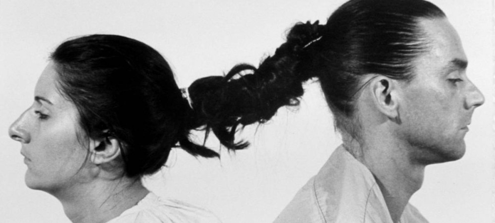 Man and woman photographed from the side with intertwined hair.
