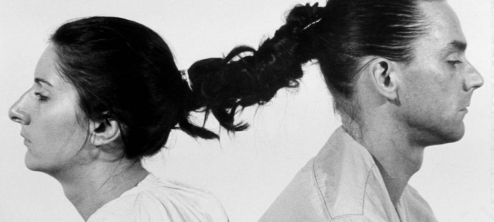 Man and woman photographed from the side with intertwined hair.