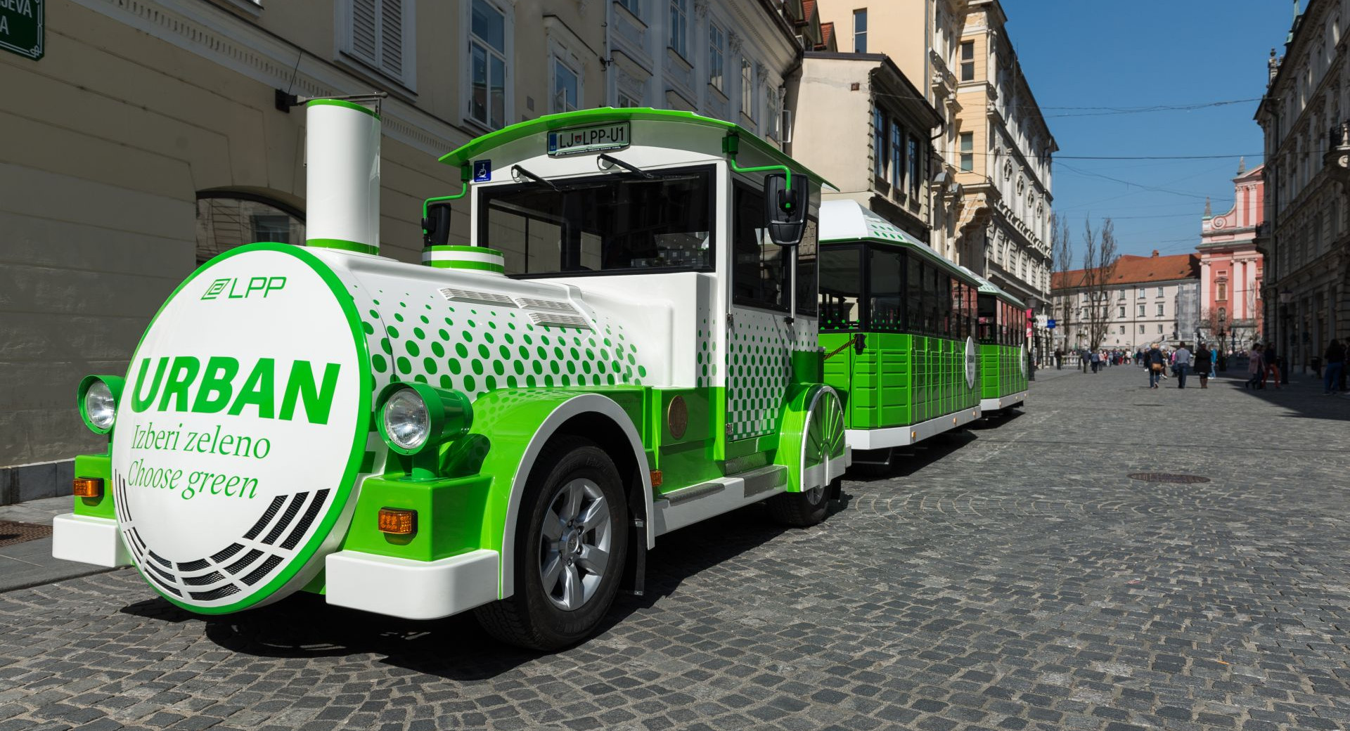 Petit train touristique vert et blanc dans la vieille ville.