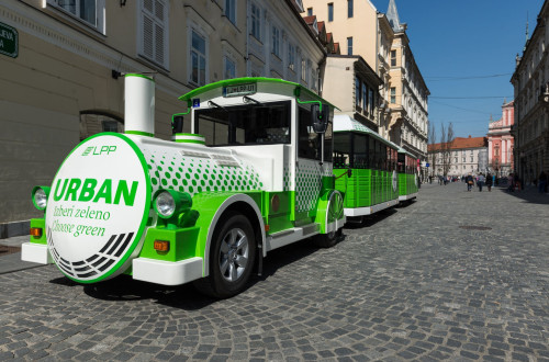 Green and white tourist train in the old town centre.