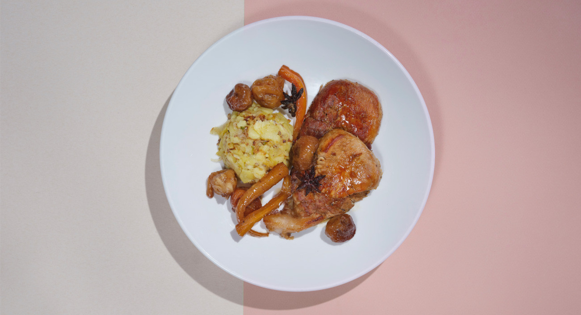 A white plate on a beige and pink base. Neatly arranged slices of roast, potatoes, and fig slices on the plate.