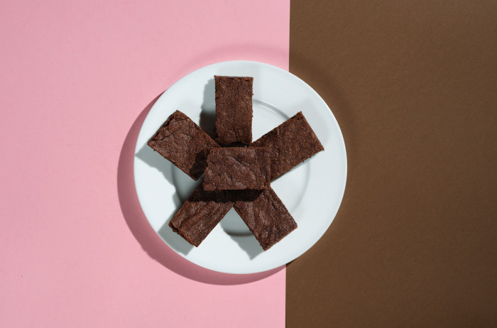 A white plate on a pink and brown base. Chocolate cubes are arranged in a star shape on the plate.