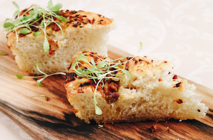 Two pieces of pogaca on a wooden board, garnished with fresh herbs.