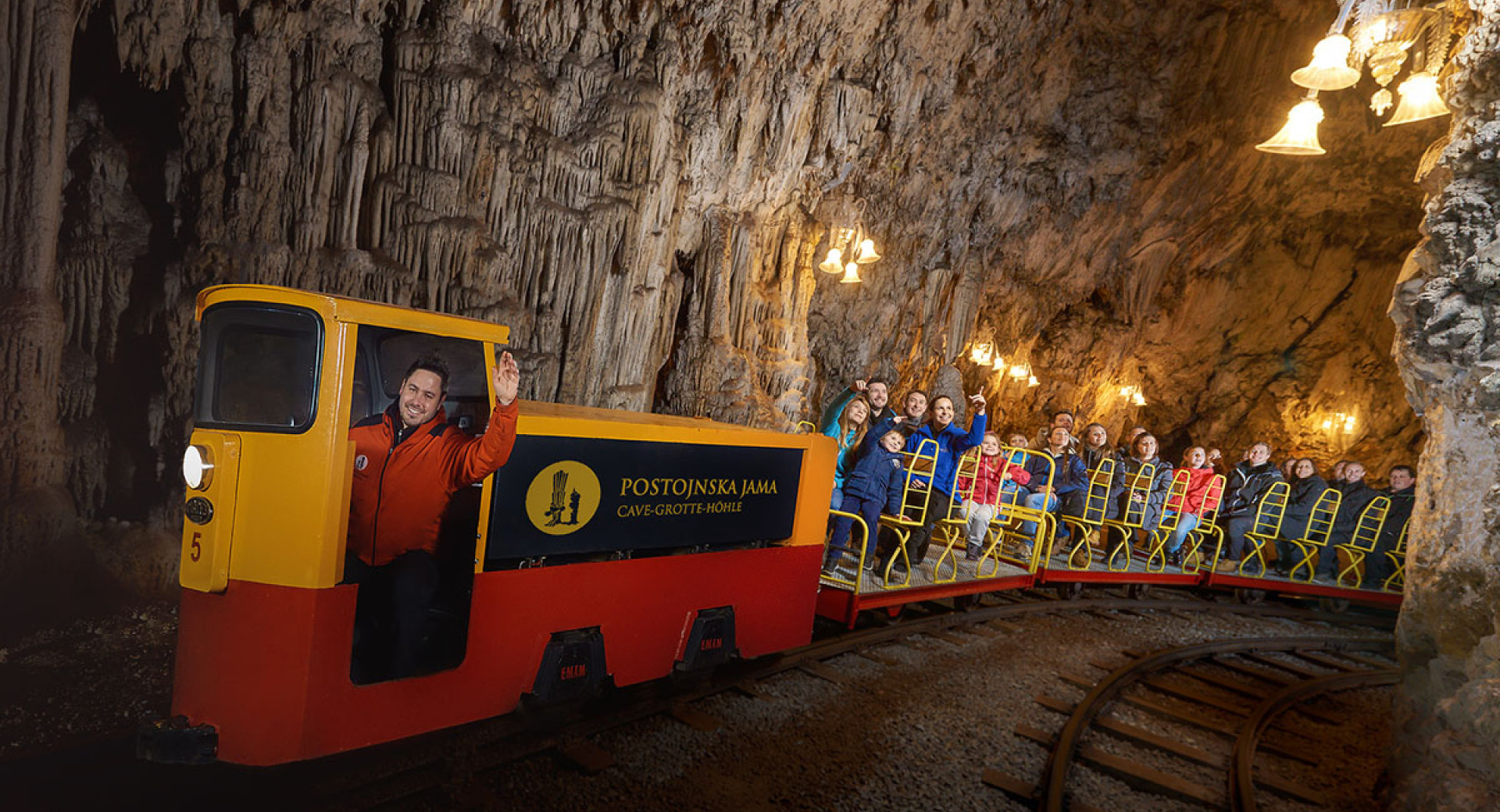 Persone sul trenino turistico nella grotta.