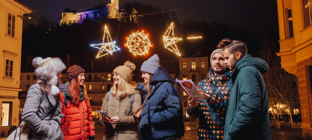 Fantje in dekleta v soju prazničnih luči na trgu pod gradom.