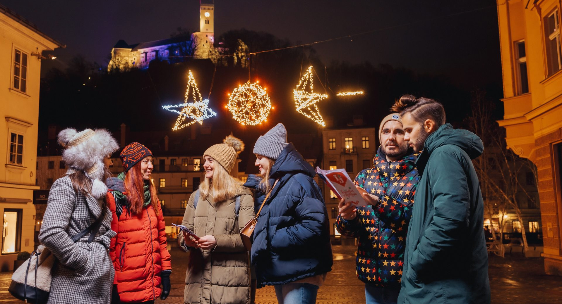 Garçons et filles sous l'éclat des illuminations festives sur la place au pied du château.