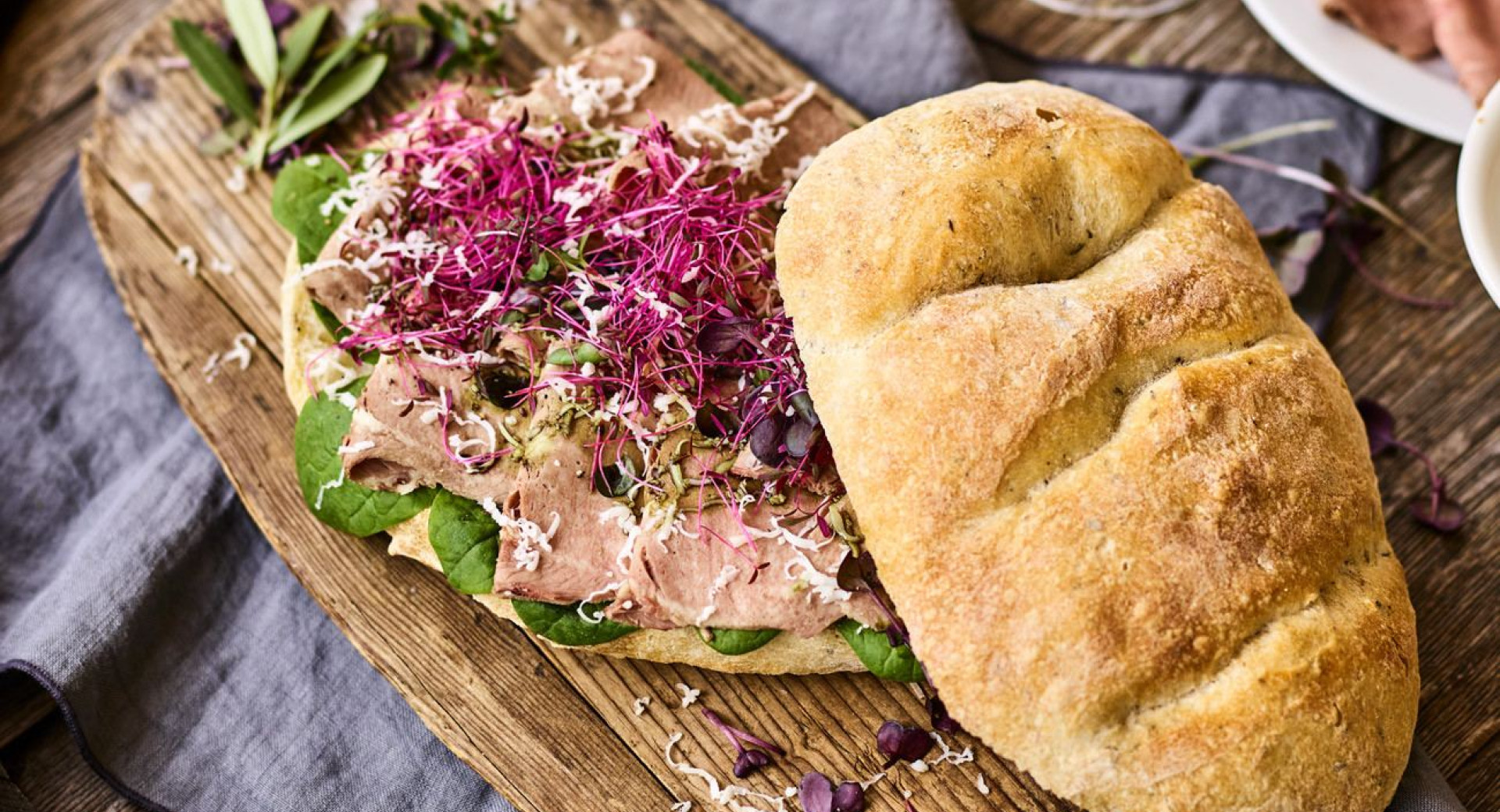 A richly filled sandwich on a wooden cutting board.