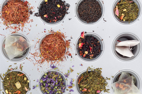 Fotografija čaja in čajnih vrečk iz ptičje perspektive. Listi čajev so v različnih barvah.