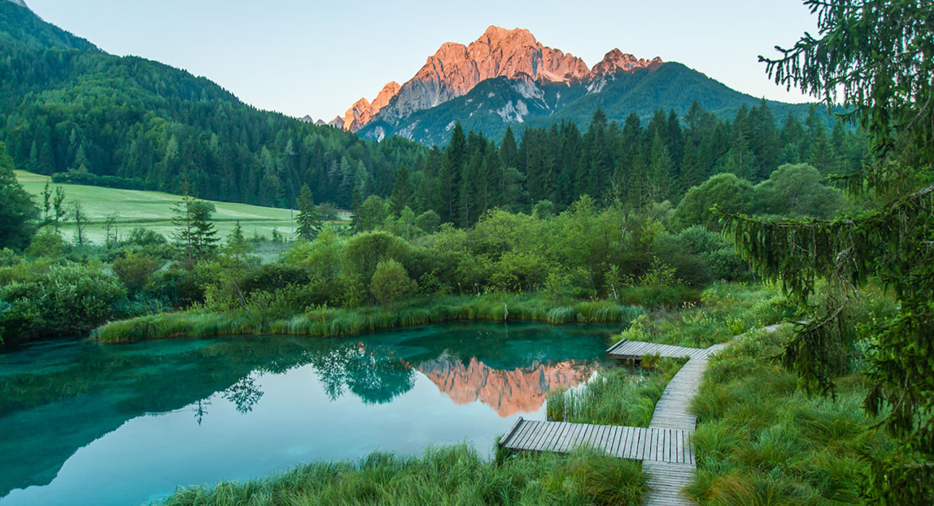 Parco Naturale Zelenci, con montagne sullo sfondo al tramonto.