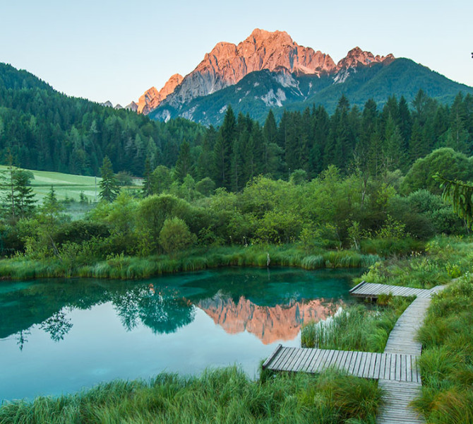 Zelenci Natural Park, with mountains in the background at sunset.