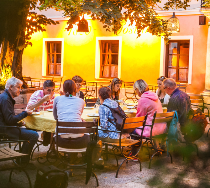 Persone sedute a un tavolo davanti a un ristorante che mangiano.