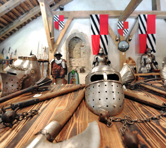 Una collezione di armature e armi medievali esposta su un tavolo di legno nella mostra del castello.