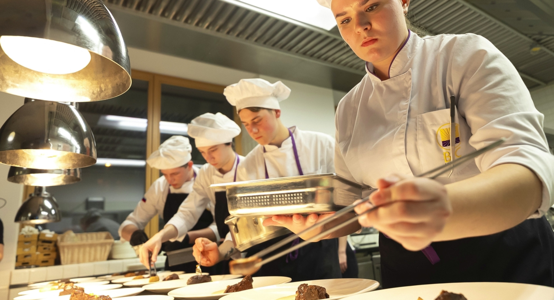 Mladi kuharji med pripravo jedi za postežbo.