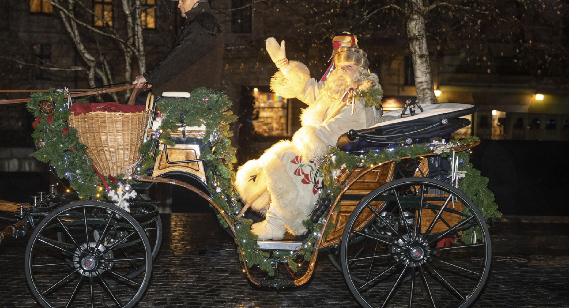 Dedek Mraz maha z okrašene kočije.