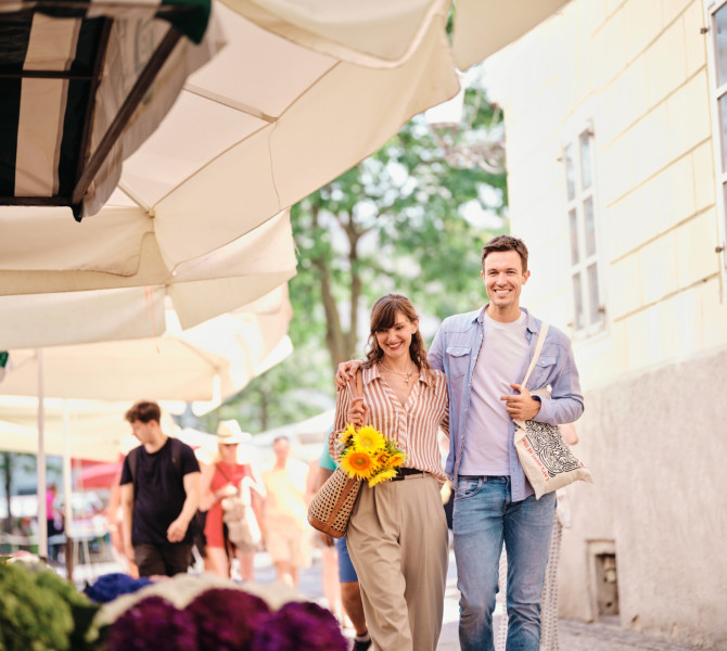 Un couple se promenant au marché, la jeune femme a des tournesols dans son sac.