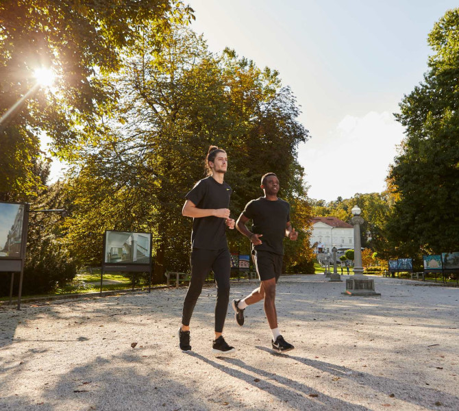 Dva tekaca teceta skozi park, kjer je razstava fotografij.